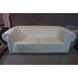 A three seat Chesterfield sofa in white buttoned faux leather upholstery