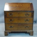 A 19th century oak bureau, the hinged lid enclosing fitted interior, above three long drawers, on