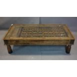 A large Indian brass clad hardwood table, carved and pierced with glass top, on turned legs, H.45