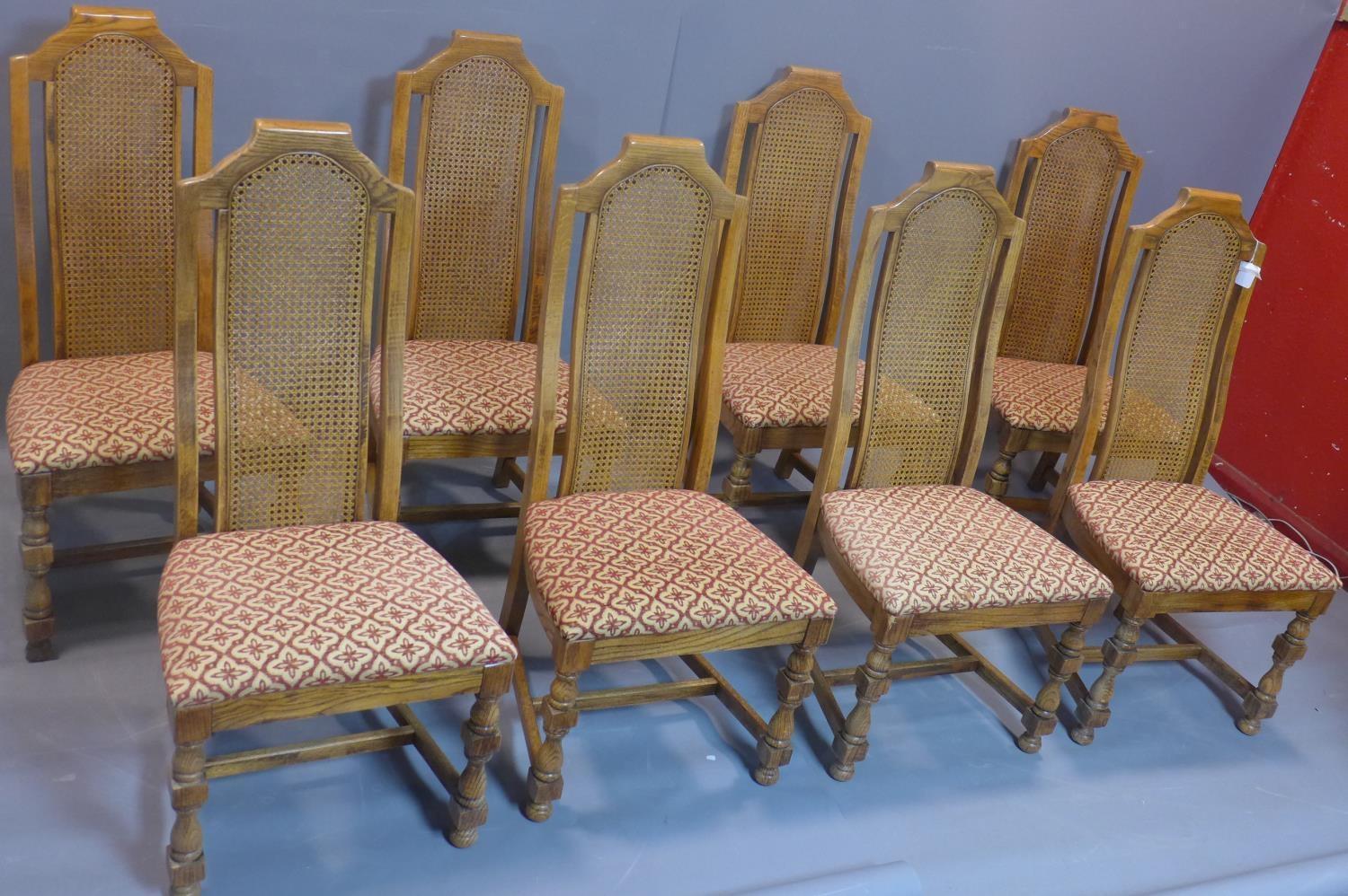 A set of eight fruitwood dining chairs with caned rattan back rests, having floral upholstered