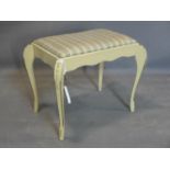 A 20th century cream painted stool, with striped upholstered seat, on floral carved cabriole legs,