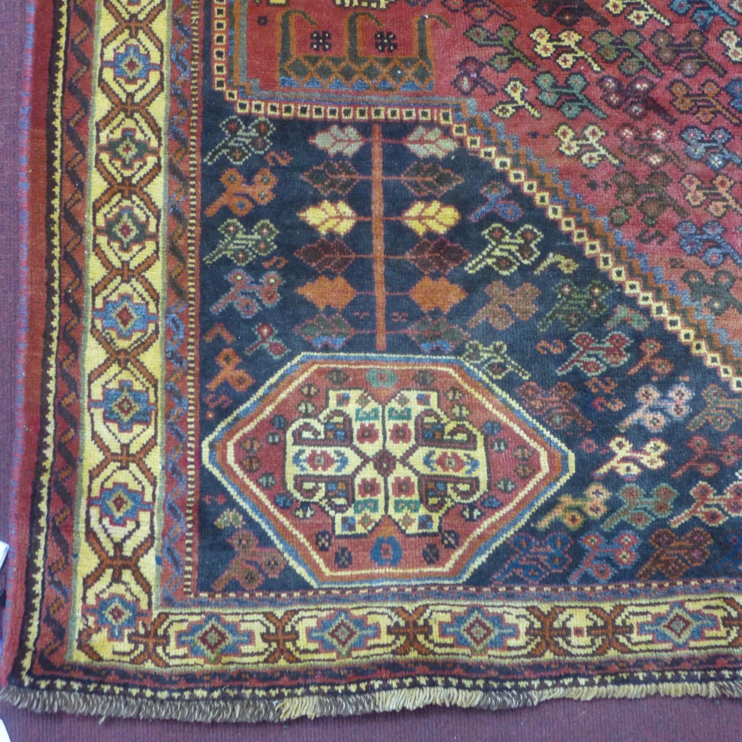 A Persian Qashqai carpet, central floral medallion and stylised petal motifs on a rouge field, - Image 3 of 5