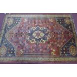 A Persian Qashqai carpet, central floral medallion and stylised petal motifs on a rouge field,