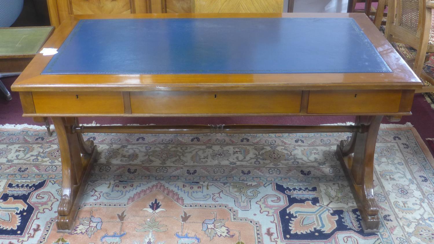 A 19th century mahogany library table, with scrolling supports, having blue leather skiver above two