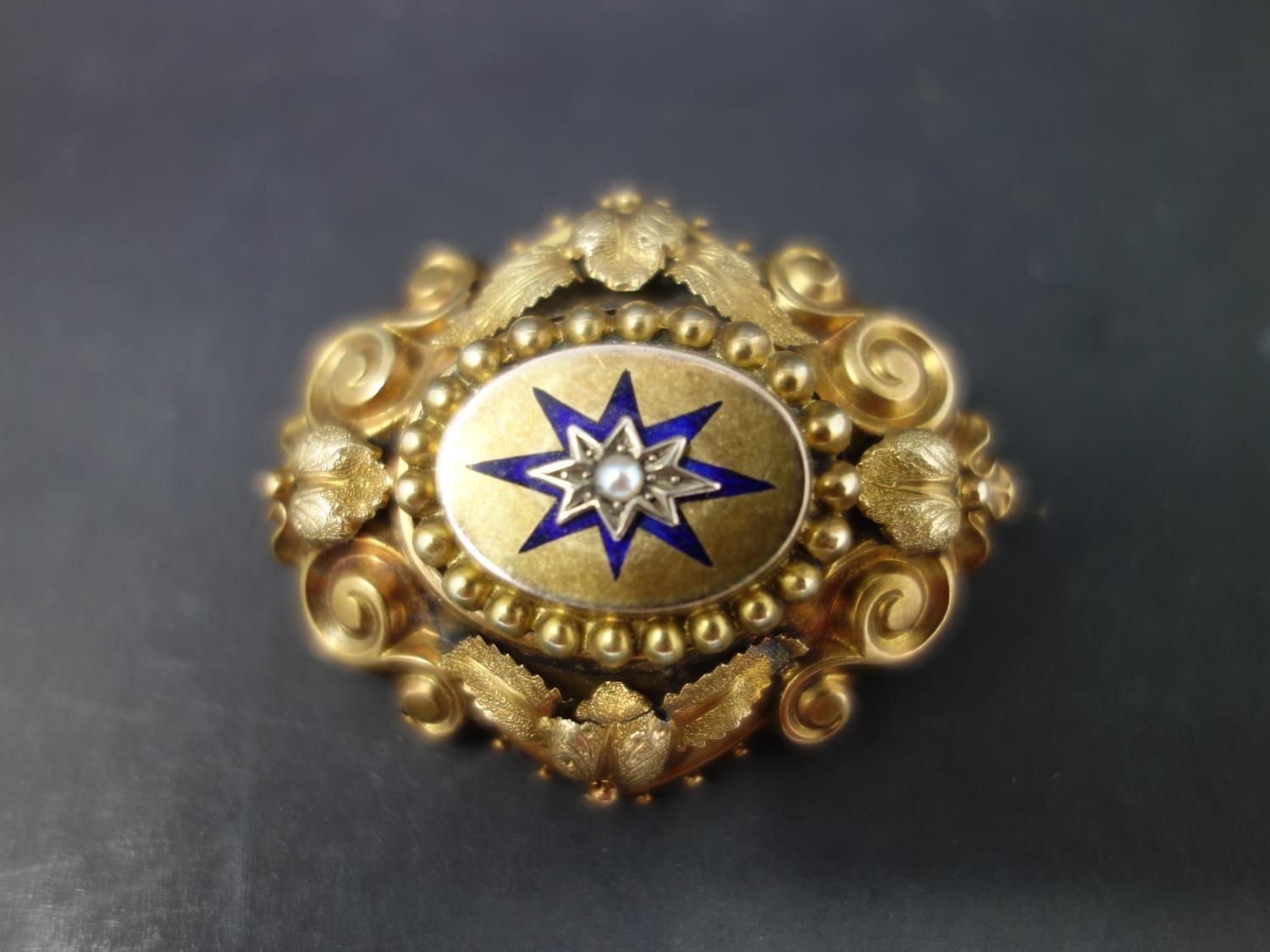 A Victorian yellow metal memento mori brooch, with scrolling decoration and central seed pearl in