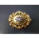 A Victorian yellow metal memento mori brooch, with scrolling decoration and central seed pearl in