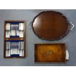 A wooden tray with silver handles and feet together with another tray and silver plated box of