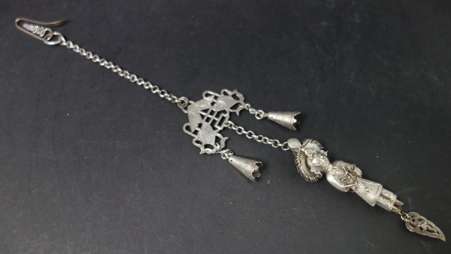 A late 19th century Chinese white metal chatelaine, with bells, pierced fish plaque and figure of