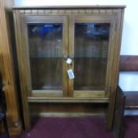 A mid century Ercol teak cabinet, with two glazed doors, label to verso, H.126 W.93 D.33cm