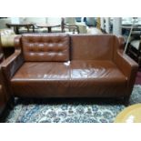 A brown leather 2 seater sofa, with button back cushion (missing the other cushion), on tapered