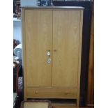 An oak wardrobe, with two doors above single long drawer and undertier rack, on square tapered legs,
