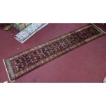 A north west Persian runner with repeating stylised petal motifs, on a midnight ground, contained by