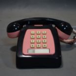 A vintage Bakelite black and pink telephone
