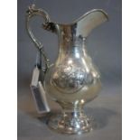 An American silver ewer, with repousse embossed vignette of flowers and vacant cartouche on an