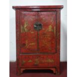 A Chinese red and black lacquered side cabinet, having two doors, decorated in gilt with padogas and