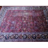 A large north west Persian Meshad carpet, with repeating floral motifs, on a rouge ground, contained