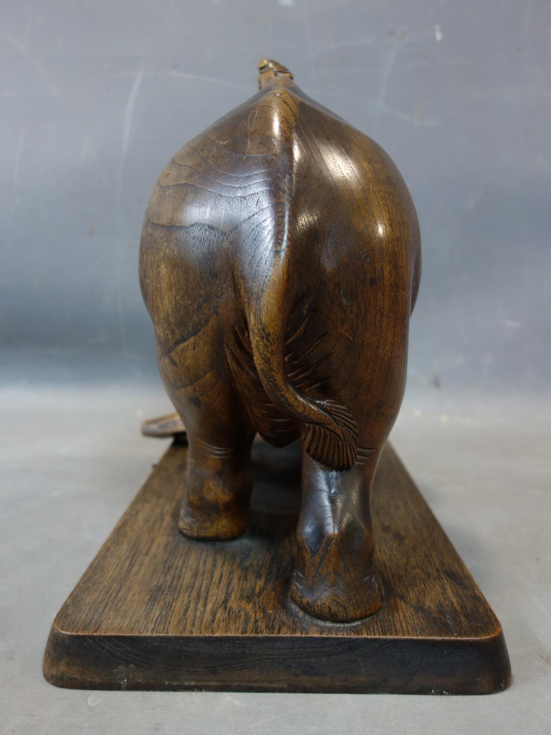 A teak carving of a man riding an elephant picking up a log, with bone tusks, on rectangular teak - Image 3 of 5