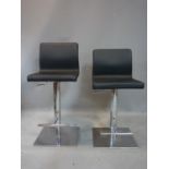 A pair of chrome and black leather adjustable bar stools