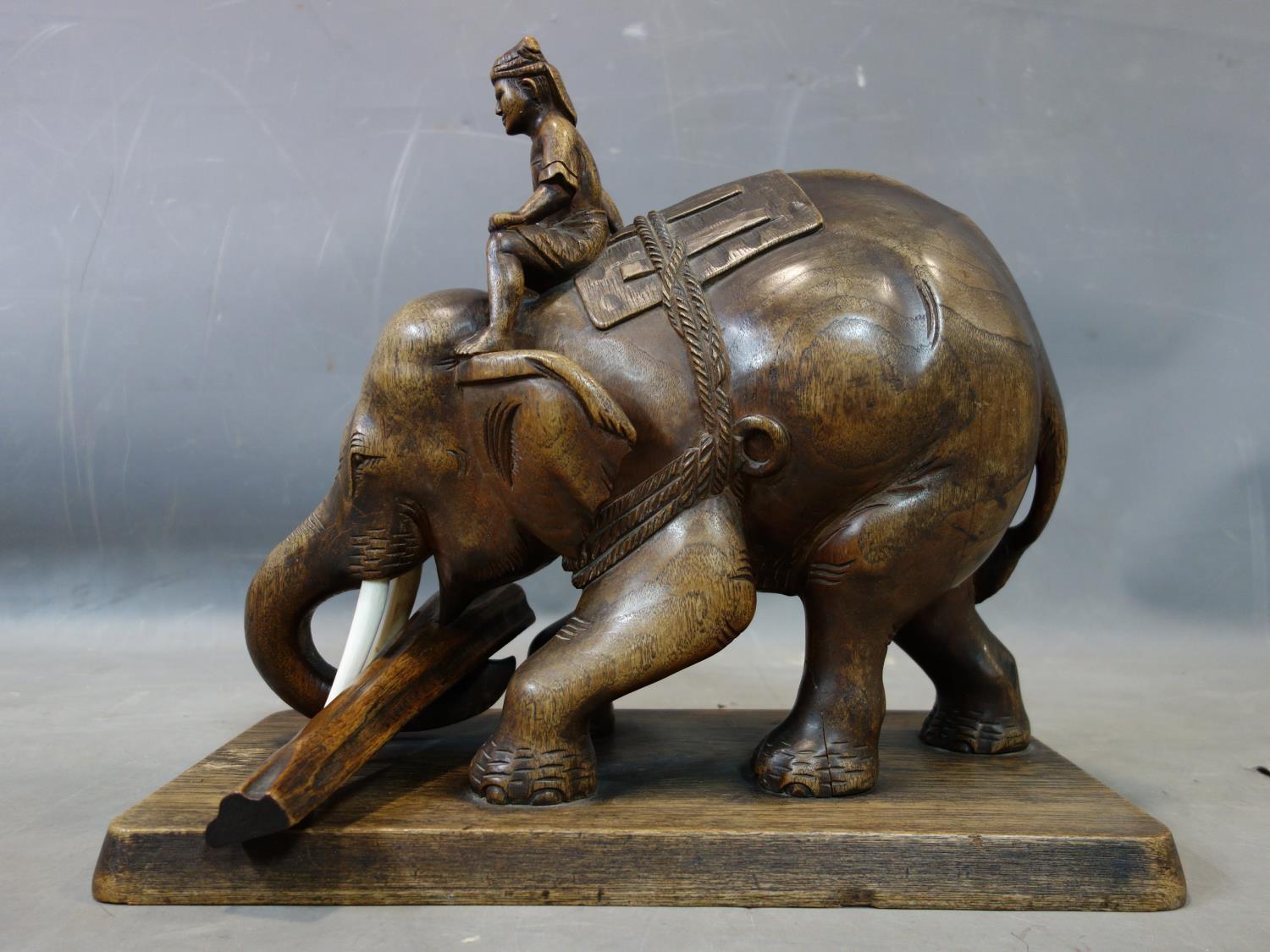 A teak carving of a man riding an elephant picking up a log, with bone tusks, on rectangular teak - Image 2 of 5