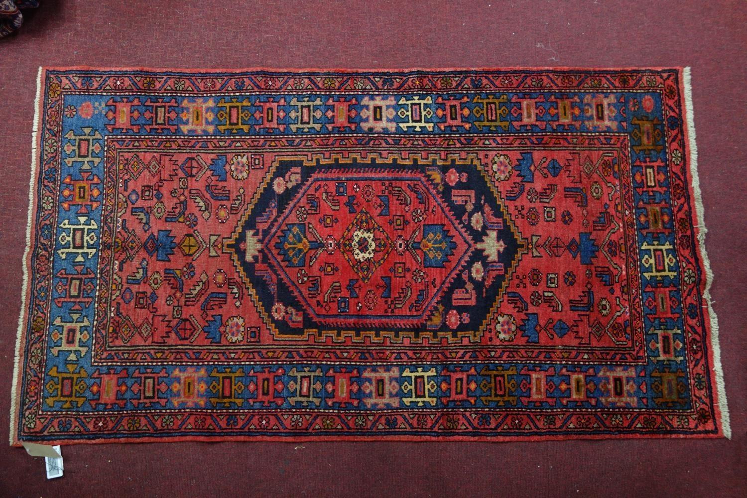 A North West Persian Zanjan rug, central diamond medallion with repeating petal motifs on a rouge