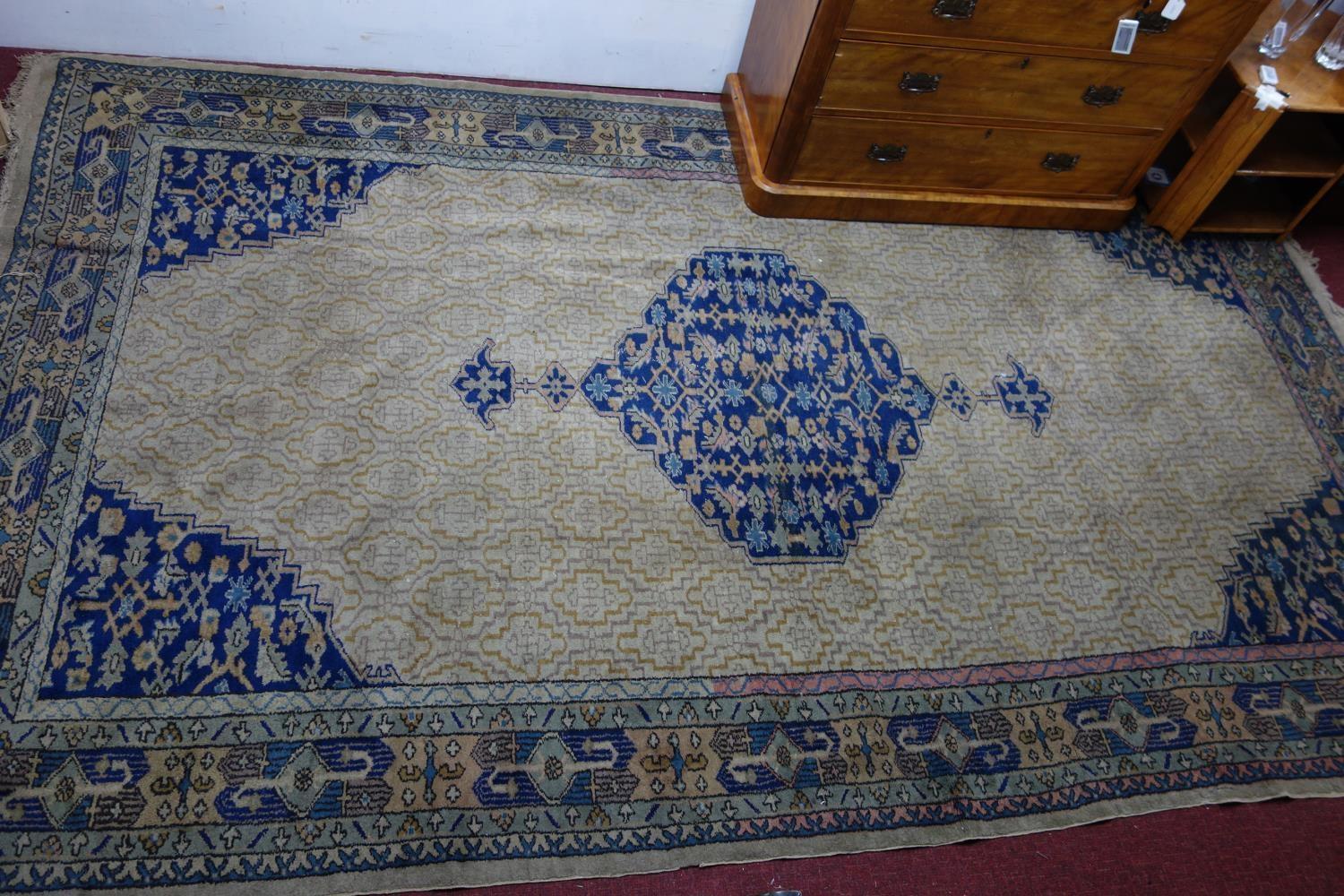 A Turkish carpet with central medallion on a tan ground with repeating stylised floral motifs,