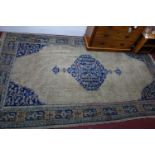 A Turkish carpet with central medallion on a tan ground with repeating stylised floral motifs,