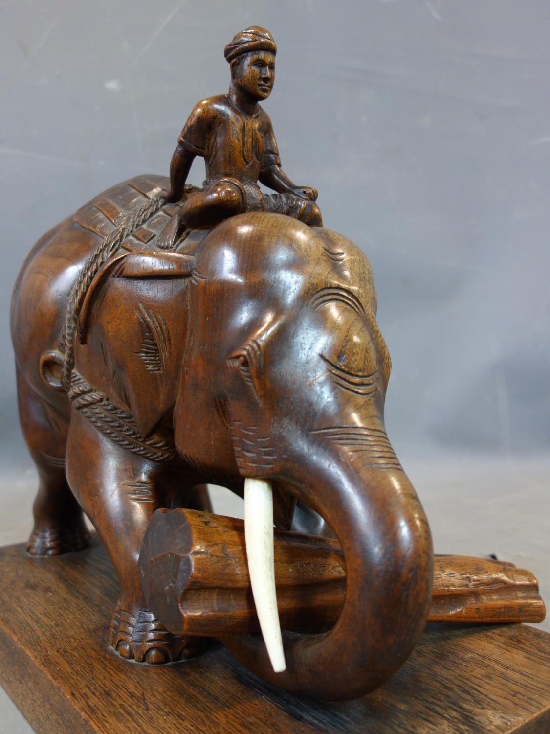 A teak carving of a man riding an elephant picking up a log, with bone tusks, on rectangular teak - Image 5 of 5