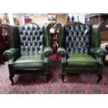 A pair of 20th century green leather wing back armchairs