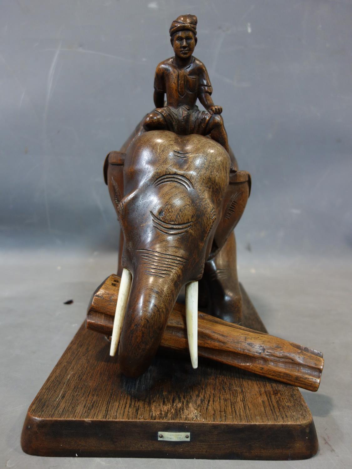 A teak carving of a man riding an elephant picking up a log, with bone tusks, on rectangular teak - Image 4 of 5