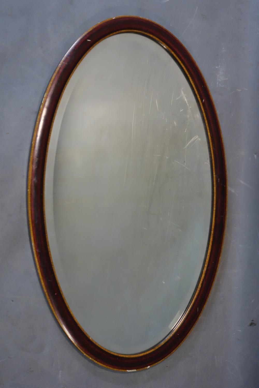 An Edwardian mahogany oval mirror with satin wood inlay and bevelled plate, 74 x 44cm