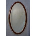 An Edwardian mahogany oval mirror with satin wood inlay and bevelled plate, 74 x 44cm