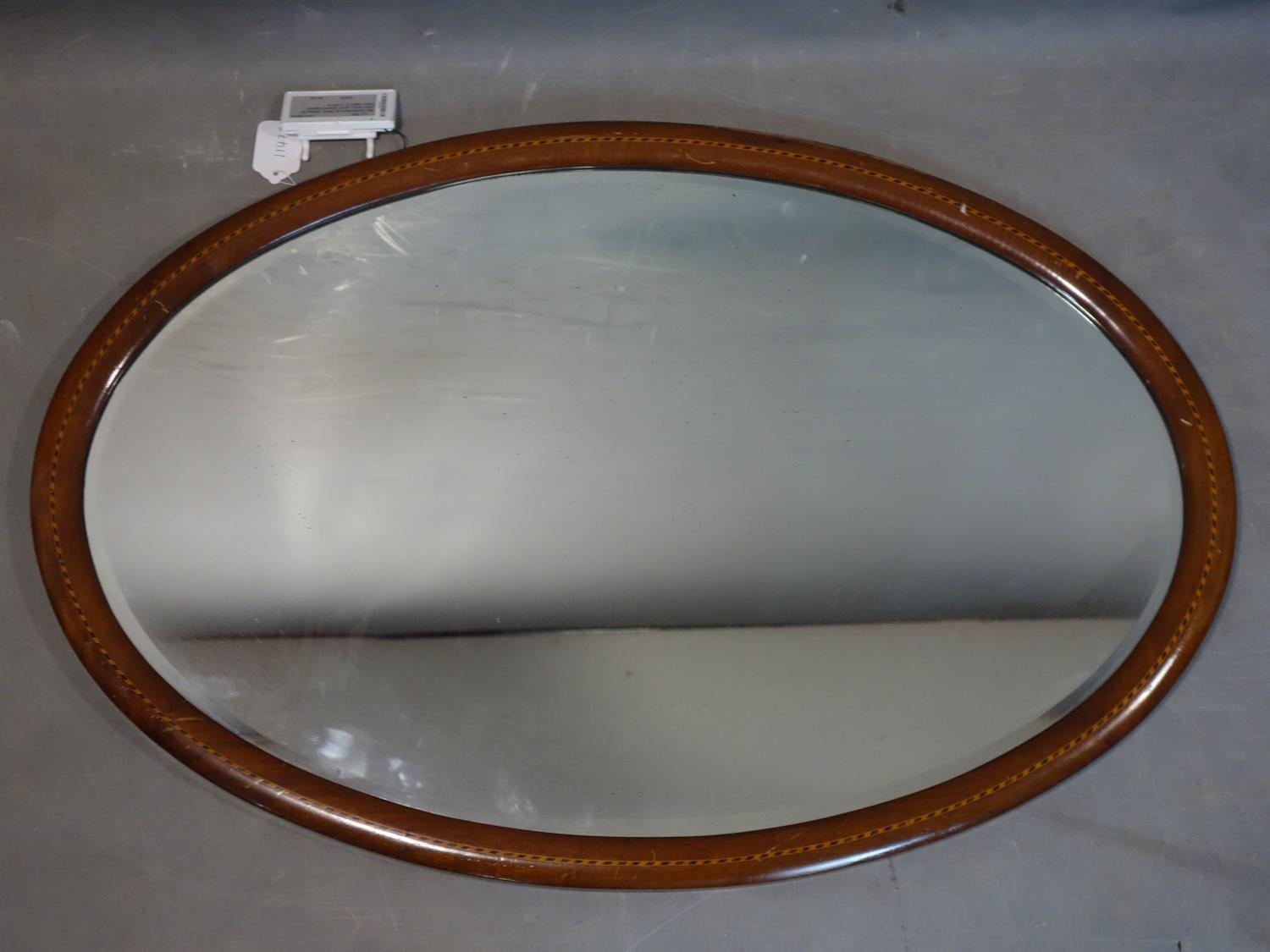 A mahogany inlaid oval wall mirror, with bevelled glass plate, 60 x 89cm