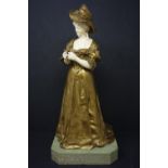 A late 19th/early 20th century gilt bronze and ivory figure of a lady in a hat, indistinctly signed,