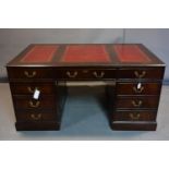 A mahogany pedestal desk, with an arrangement of seven drawers, having three section red leather