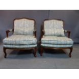 A pair of 20th century mahogany armchairs, with floral upholstery, raised on carved cabriole legs,