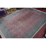 A large 20th century Middle Eastern carpet, with repeating geometric motifs, on a salmon pink