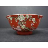 A Chinese red glazed bowl decorated with blossoms on a branch, with Chinese characters to body,