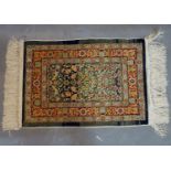 A small signed silk Hereke mat, with floral medallion on a blue ground, contained by floral