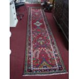 A Central Persian Sarouk runner, central floral medallion and repeating petal motifs on a rouge