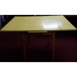 A formica topped draw-leaf table, the yellow formica top above splayed teak legs, H.80 W.121 D.81cm