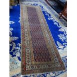 An antique Persian runner with repeating geometric motifs, on a blue ground, contained by a