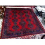 A Turkish rug, geometric medallions on a rouge field, within geometric borders, reportedly bought