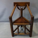 A late 19th/early 20th century oak tribal corner chair, with bobbin turned arms and carved totem
