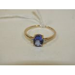 A HALLMARKED 9 CARAT GOLD TANZANITE RING, the oval tanzanite coming with a stone either side, and is