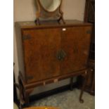 A WALNUT VENEER DRINKS CABINET ON STAND - VENEER MISSING