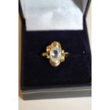 A 14K GOLD ART NOUVEAU STYLE DRESS RING SET WITH A LARGE CLEAR STONE AND SMALLER STONES TO SHOULDERS