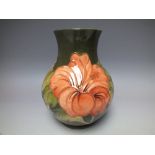 A MOORCROFT 'HIBISCUS' PATTERN BALUSTER VASE, green ground with typical tubelined decoration,