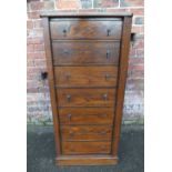 AN EDWARDIAN OAK WELLINGTON CHEST, with seven drawers and locking bar, H 122 cm, W 55.5 cm