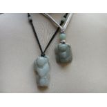 TWO CHINESE CELADON CARVED JADE FIGURAL PENDANTS, finely carved in shallow relief, one in the form