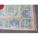 AN EASTERN EARLY 20TH CENTURY WOOLLEN RUG / CARPET, the central shaped cartouche within a red shaped